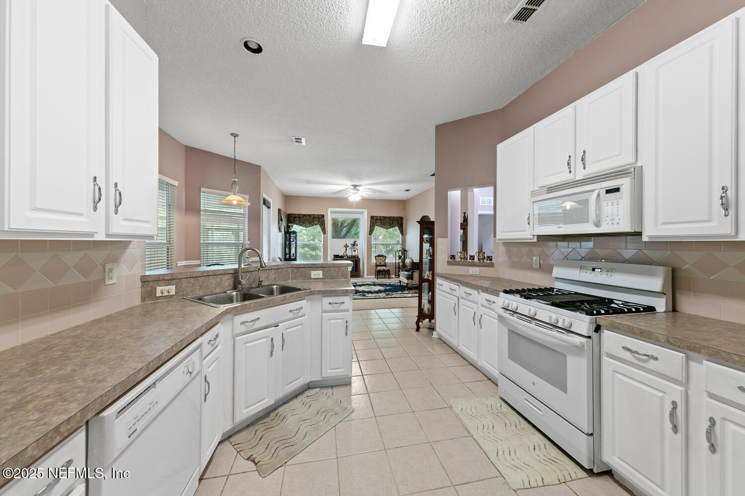4219 Woodley Creek Road Jacksonville, FL 32218 - Photo 7 of 28 a large white kitchen with stainless steel appliances granite countertop a sink and dishwasher a stove top oven with white cabinets