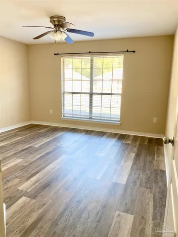 a view of an empty room with window and a chandelier fan