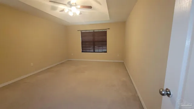 an empty room with a chandelier fan and windows