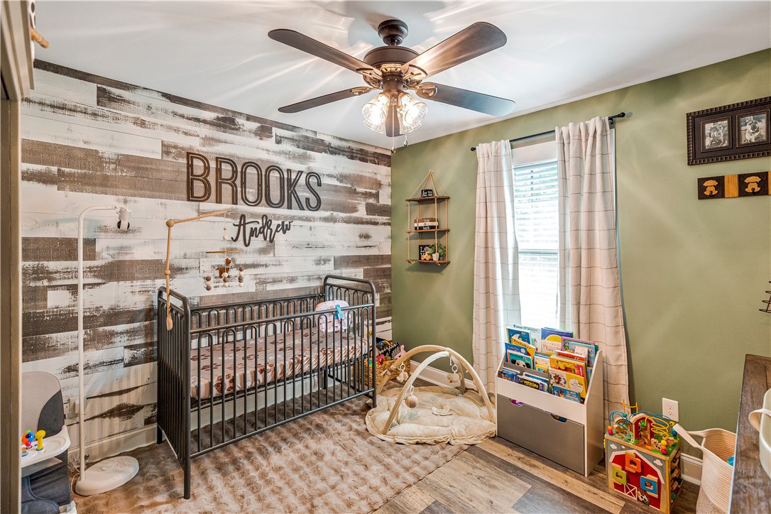 842 Conneross Road Townville, SC 29689 - Photo 21 of 34 A comforting nursery showcasing a distinct wood-paneled accent wall and practical overhead lighting.