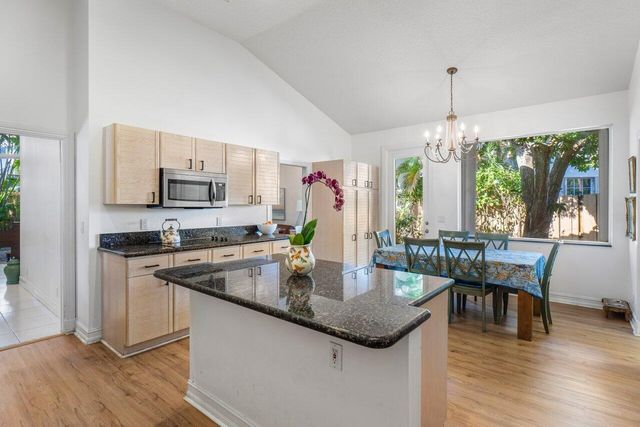 a kitchen with kitchen island granite countertop a stove a sink a dining table and chairs with wooden floor