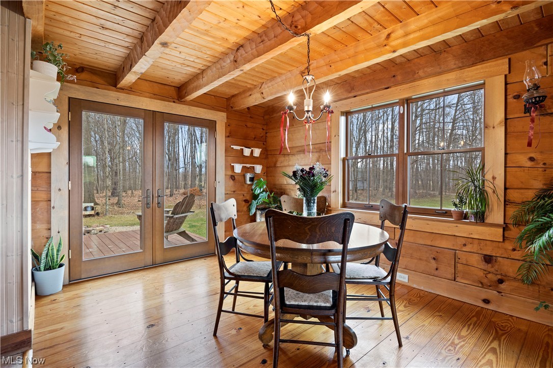 9485 Stone Road Litchfield, OH 44253 - Photo 15 of 50 Dining room with a notable chandelier, wooden ceiling, wood walls, light hardwood / wood-style flooring, and french doors