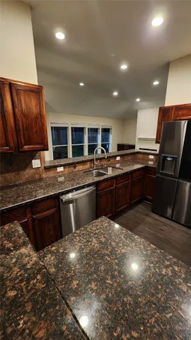 a kitchen with stainless steel appliances granite countertop wooden cabinets a stove a sink and a microwave