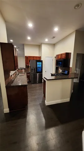 a kitchen with stainless steel appliances kitchen island granite countertop a stove a refrigerator a sink and a microwave