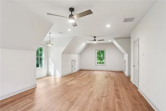 an empty room with wooden floor chandelier fan and windows