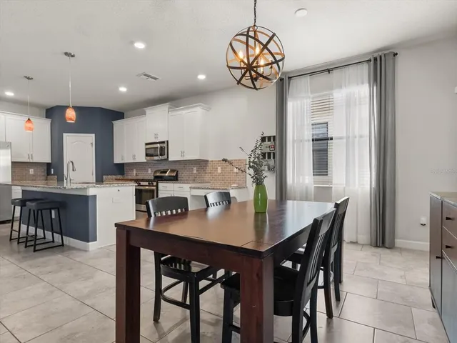 a kitchen with a dining table chairs stainless steel appliances and cabinets