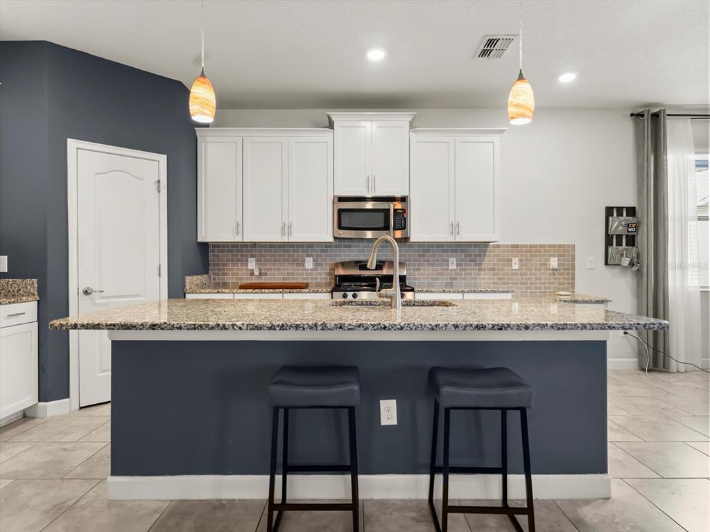 15433 Porter Road Winter Garden, FL 34787 - Photo 19 of 46 a kitchen with granite countertop a sink white cabinets and stainless steel appliances