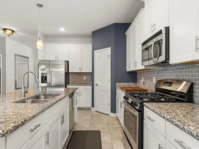 a kitchen with stainless steel appliances granite countertop a stove a sink and a refrigerator