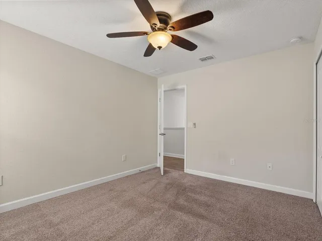 an empty room with a ceiling fan and a fan
