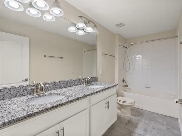 a bathroom with a granite countertop double vanity sink a mirror and a bathtub