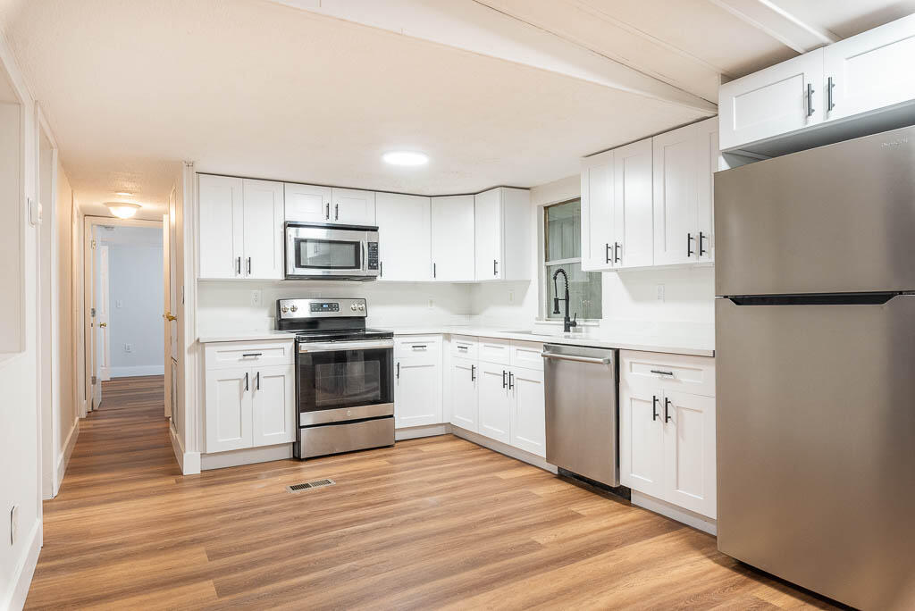 a kitchen with granite countertop white cabinets and stainless steel appliances