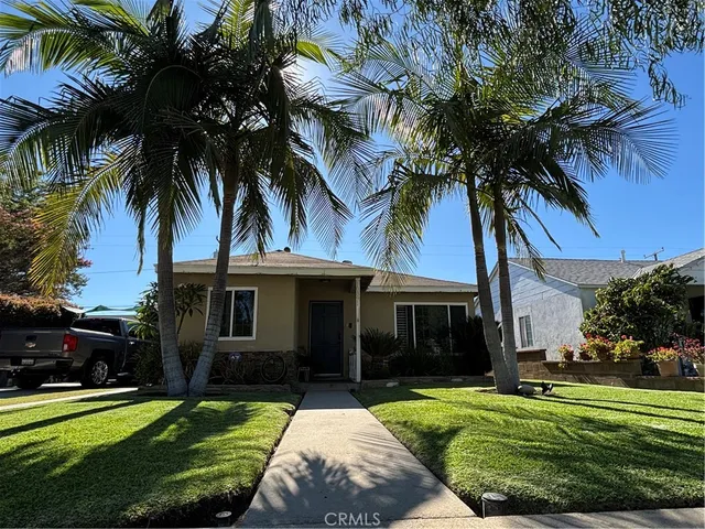 a front view of a house with a garden and trees
