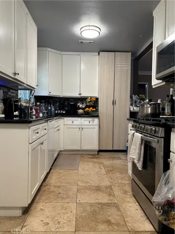 a kitchen with granite countertop a sink a stove top oven and cabinetry