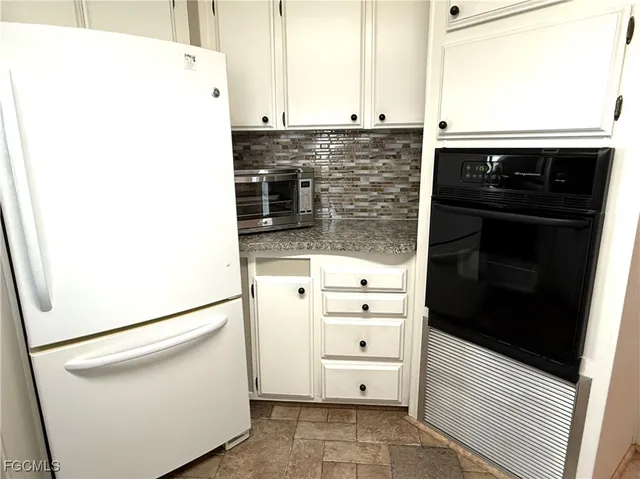 a kitchen with granite countertop white cabinets and stainless steel appliances