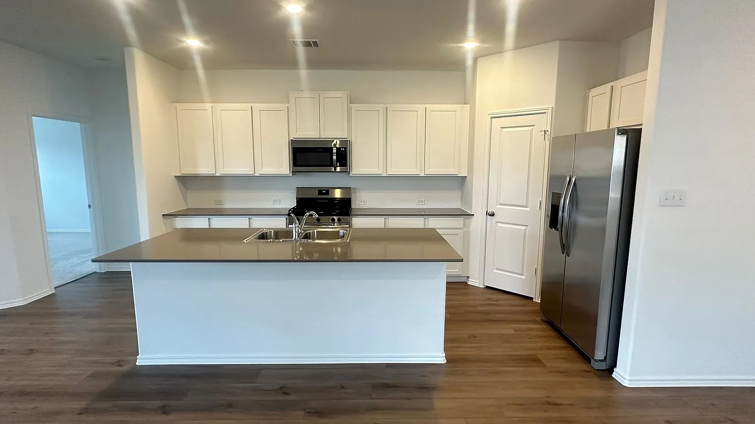 121 Tofalla Kyle, TX 78640 - Photo 5 of 37 a kitchen with stainless steel appliances a refrigerator a sink a stove a microwave and wooden floor