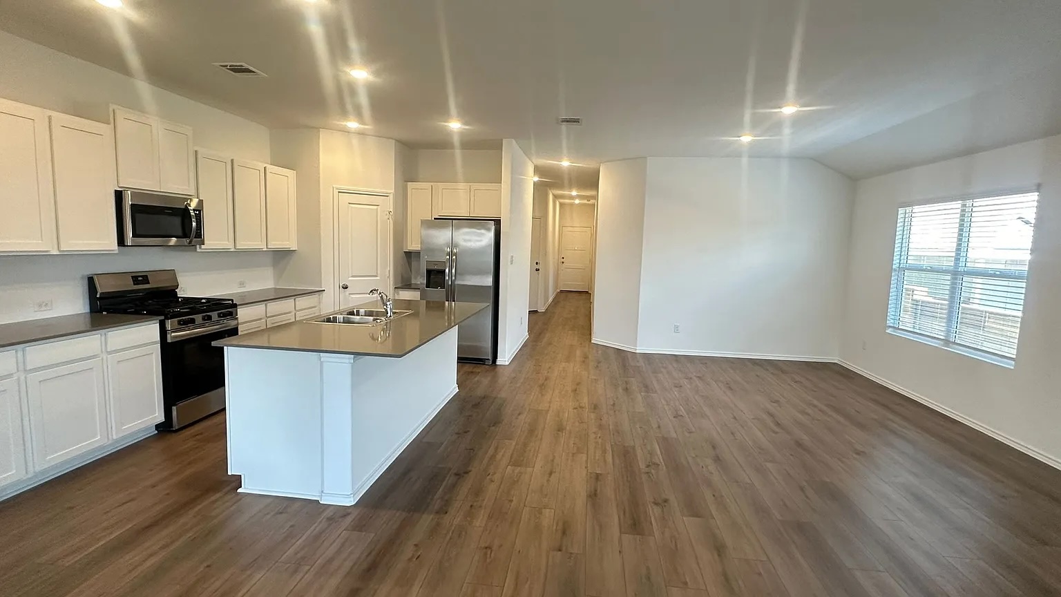 121 Tofalla Kyle, TX 78640 - Photo 7 of 37 a large kitchen with stainless steel appliances granite countertop a large stove a sink dishwasher and a microwave oven with wooden floor