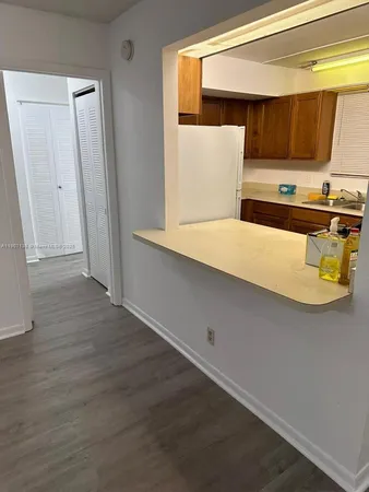 a kitchen with a wooden floor and white wall