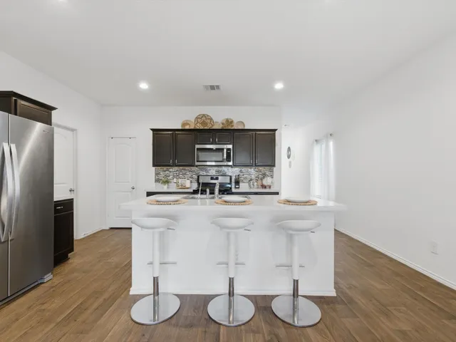 a kitchen with stainless steel appliances granite countertop a sink a stove a refrigerator cabinets and wooden floor