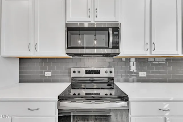 a stove top oven sitting inside of a kitchen and white cabinets