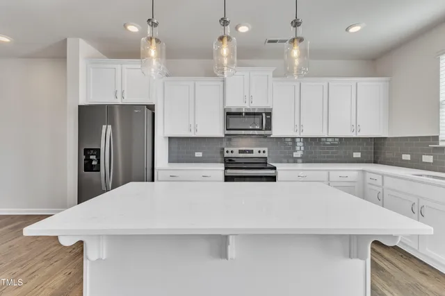 a kitchen with stainless steel appliances a refrigerator sink and white cabinets