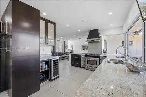 a large kitchen with stainless steel appliances granite countertop a stove top oven a sink and a refrigerator