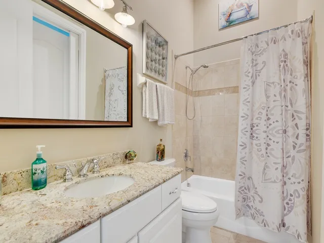 a bathroom with a granite countertop sink a toilet and a mirror