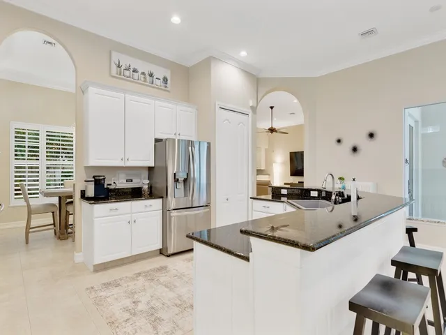 a large kitchen with granite countertop a sink refrigerator and cabinets
