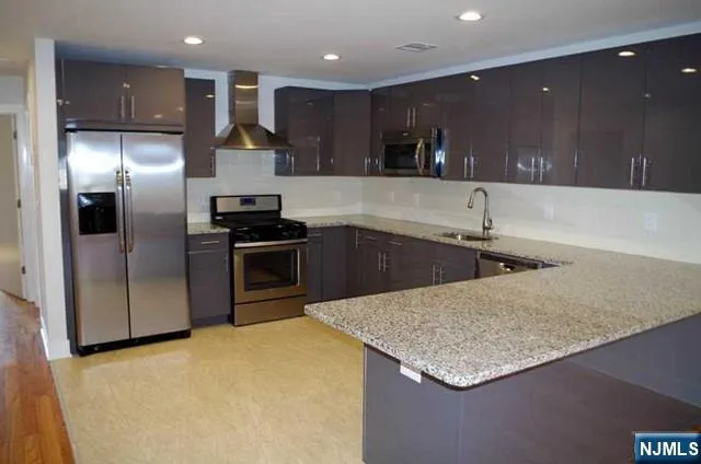 a kitchen with stainless steel appliances granite countertop a sink a stove and a refrigerator