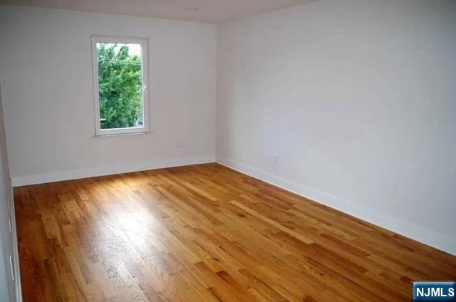a view of an empty room with wooden floor and closet