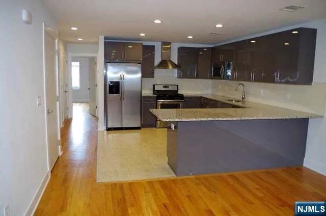 a kitchen with a sink a counter top space stainless steel appliances and cabinets