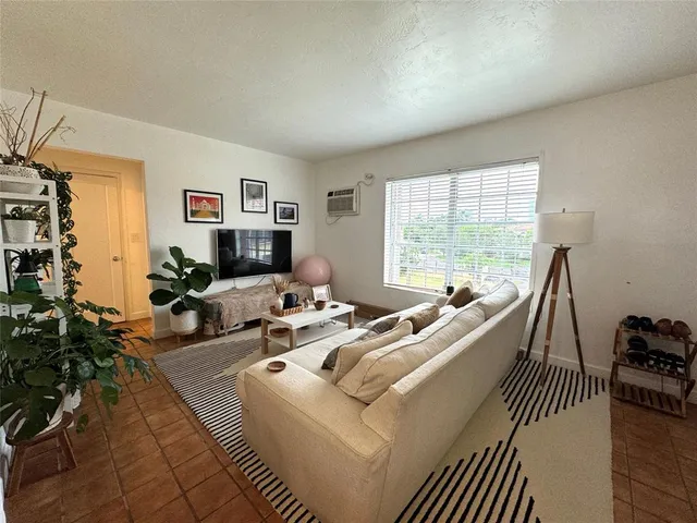 a living room with furniture floor to ceiling window and a flat screen tv