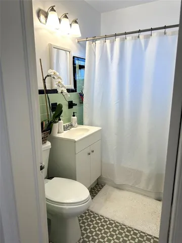 a bathroom with a sink a toilet a mirror and shower