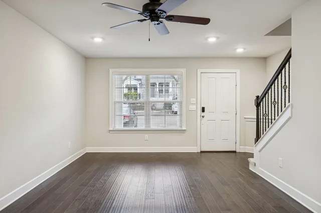 an empty room with wooden floor fan and windows