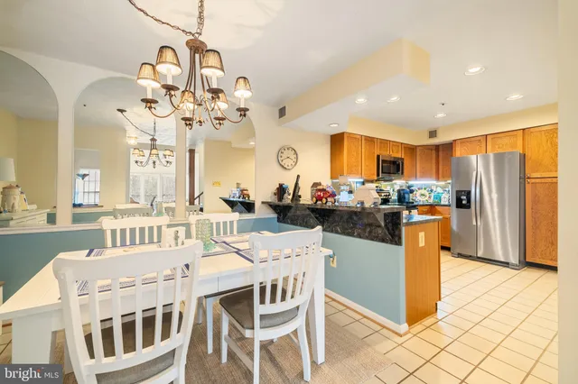 a kitchen with stainless steel appliances kitchen island granite countertop a refrigerator a stove top oven a sink dishwasher and couches with wooden floor