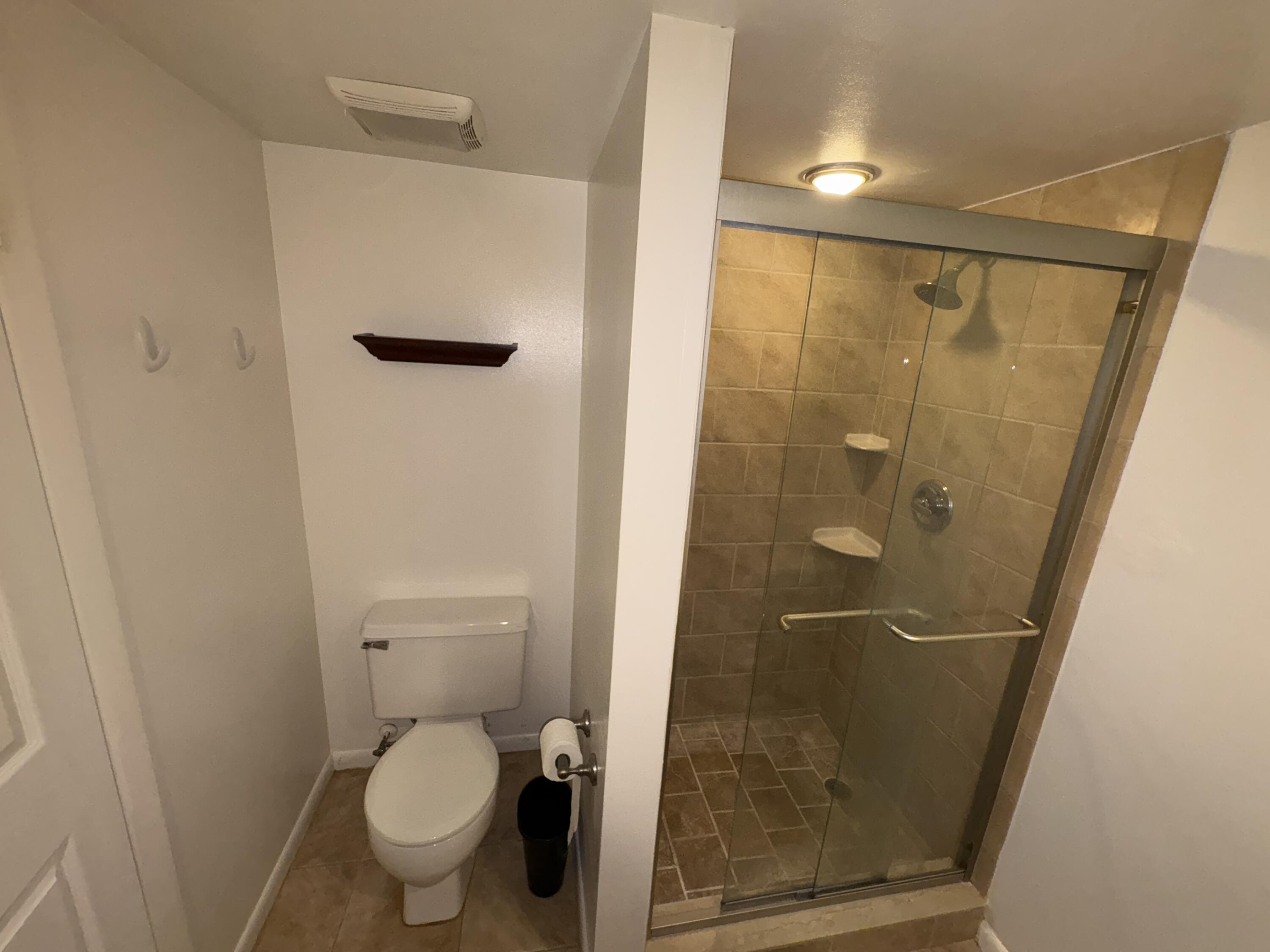 2950 Southwest 22nd Circle, Unit 4A Delray Beach, FL 33445 - Photo 18 of 42 a bathroom with a granite countertop sink toilet and shower