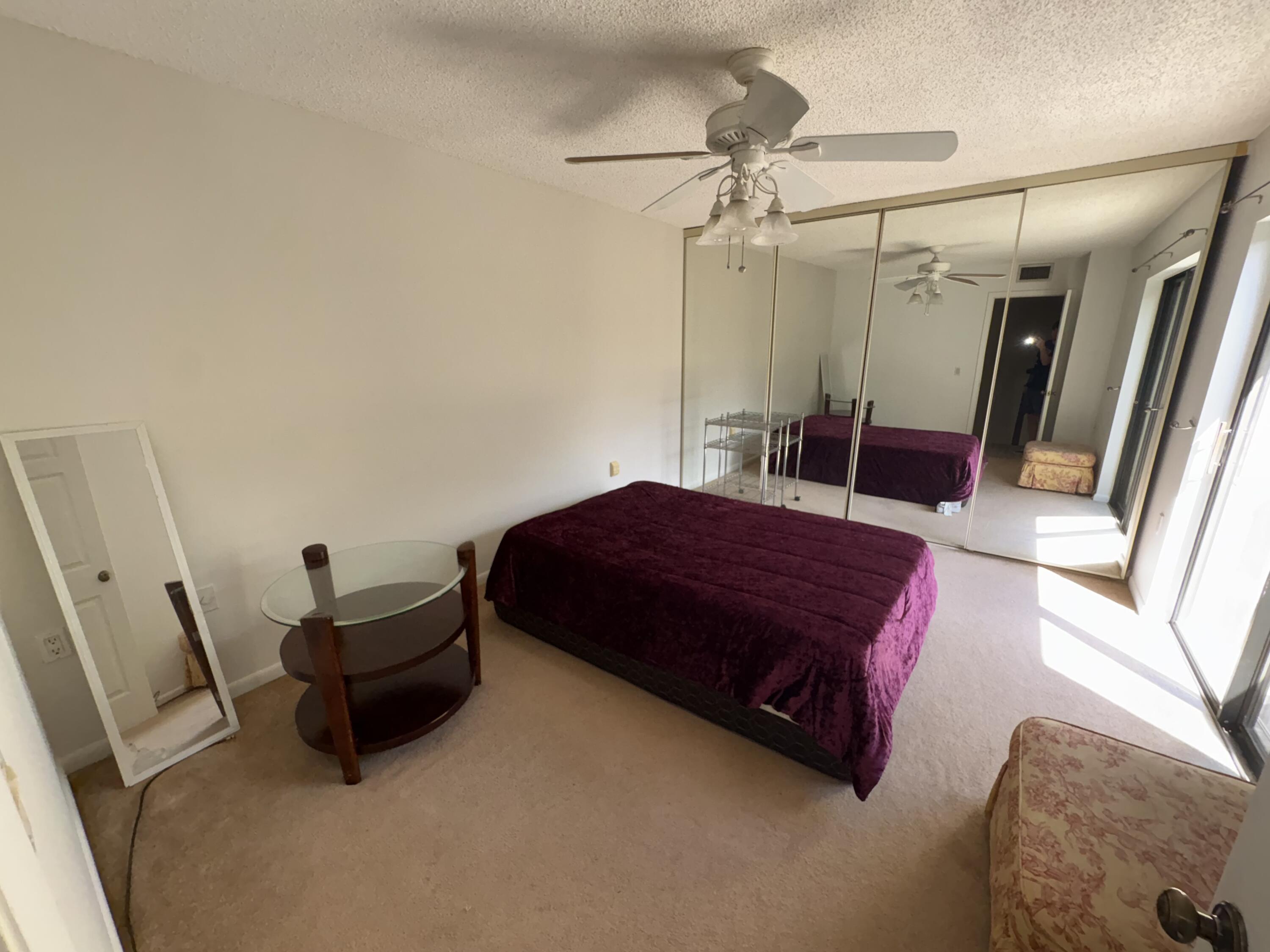 2950 Southwest 22nd Circle, Unit 4A Delray Beach, FL 33445 - Photo 24 of 42 a spacious bedroom with a bed and a mirror
