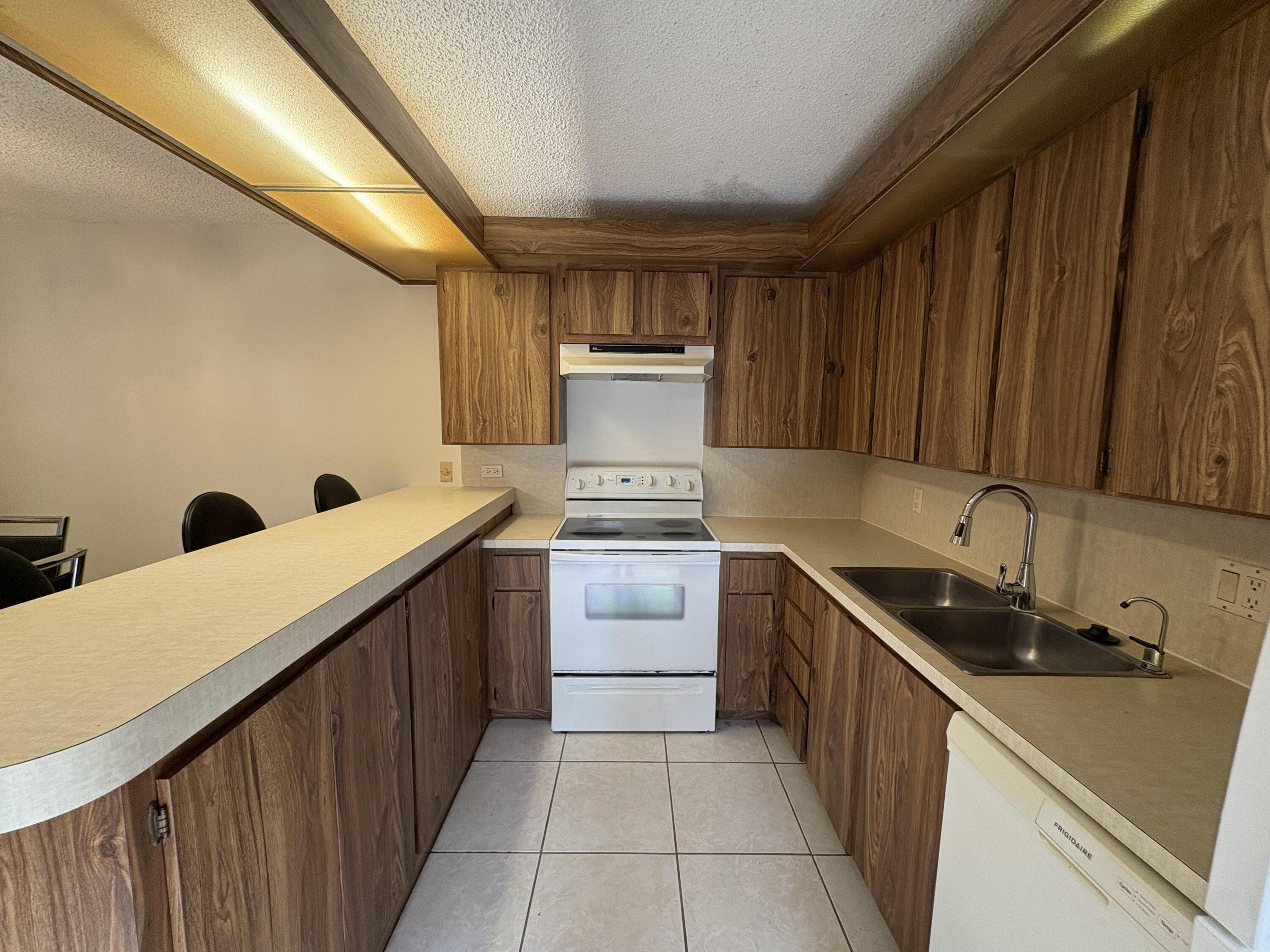2950 Southwest 22nd Circle, Unit 4A Delray Beach, FL 33445 - Photo 6 of 42 a kitchen with a sink and wooden cabinets