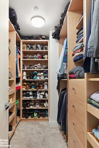 a view of walk in closet with clothes and shoes