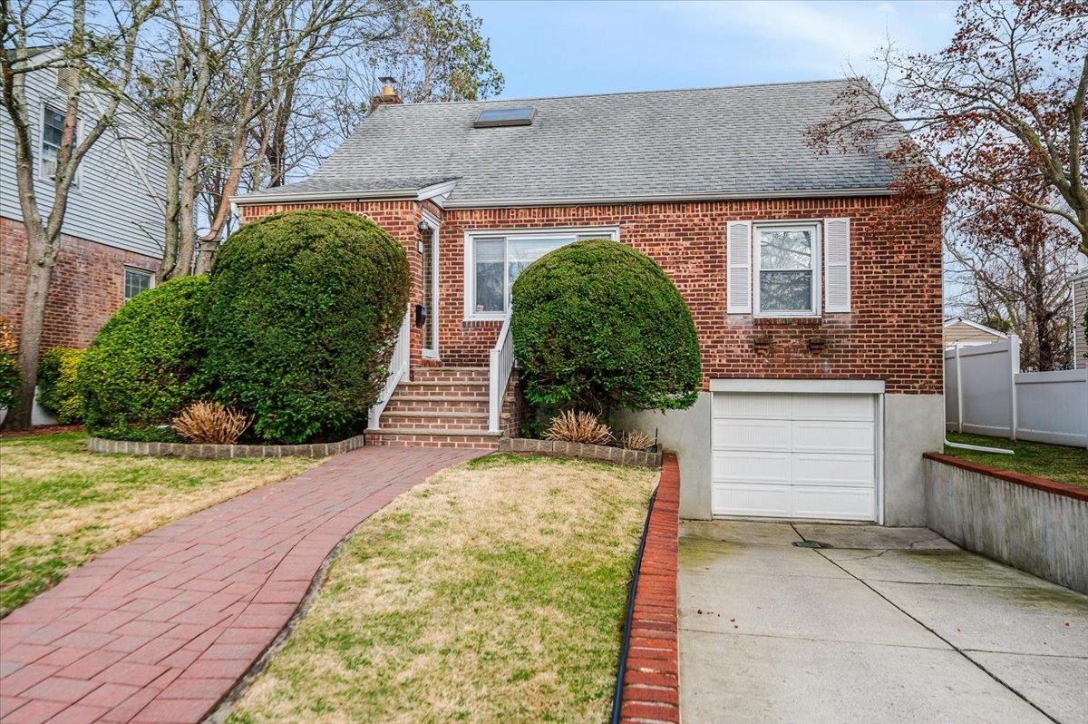 17 Firethorne Lane Valley Stream, NY 11581 - Photo 1 of 1 View of front of property with a shingled roof, an attached garage, brick siding, and concrete driveway