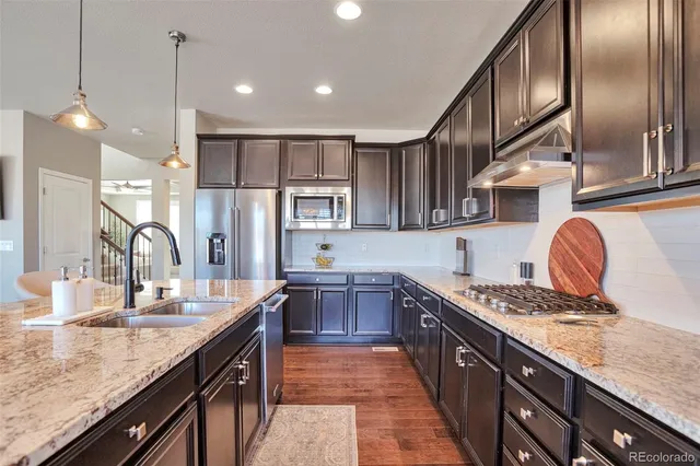 a kitchen with stainless steel appliances granite countertop a sink a stove and a wooden floors