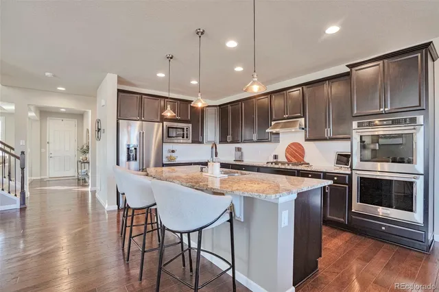 a kitchen with stainless steel appliances kitchen island granite countertop a stove a sink and a refrigerator