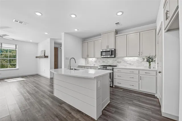 a kitchen with kitchen island granite countertop a sink cabinets and wooden floor