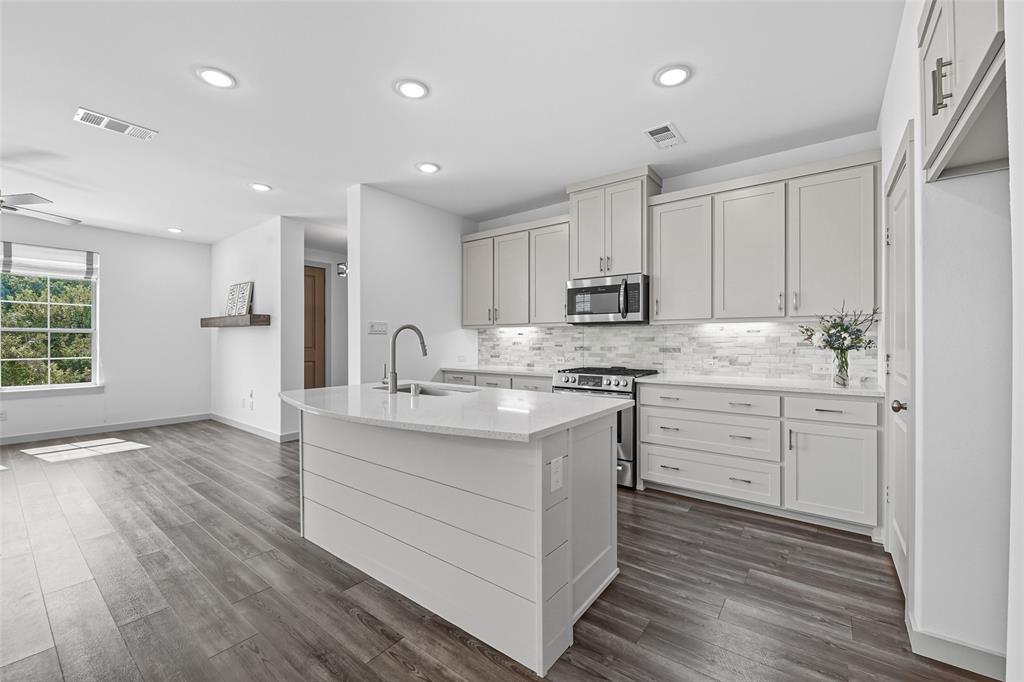 228 Spring Hill Road Flower Mound, TX 75028 - Photo 11 of 31 a kitchen with kitchen island granite countertop a sink cabinets and wooden floor