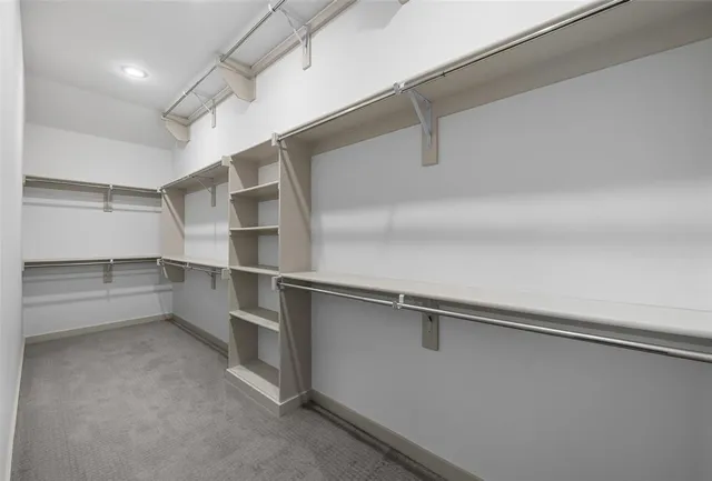 an empty room with chandelier fan and windows