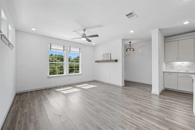 a view of an empty room with a window and wooden floor