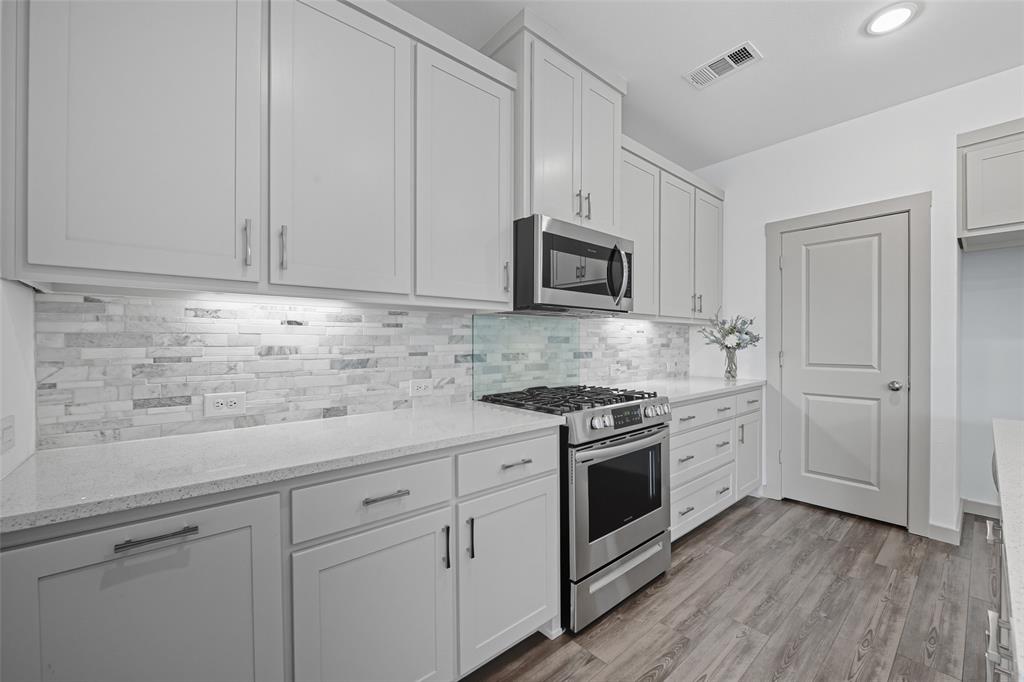 228 Spring Hill Road Flower Mound, TX 75028 - Photo 10 of 31 a kitchen with cabinets stainless steel appliances and wooden floor