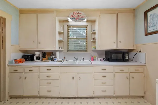 a kitchen with white cabinets and sink