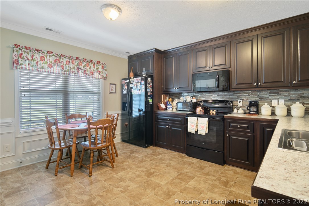 2511 Wade-Stedman Road Stedman, NC 28391 - Photo 12 of 47 a kitchen with stainless steel appliances granite countertop a stove top oven a refrigerator a sink a dining table and chairs