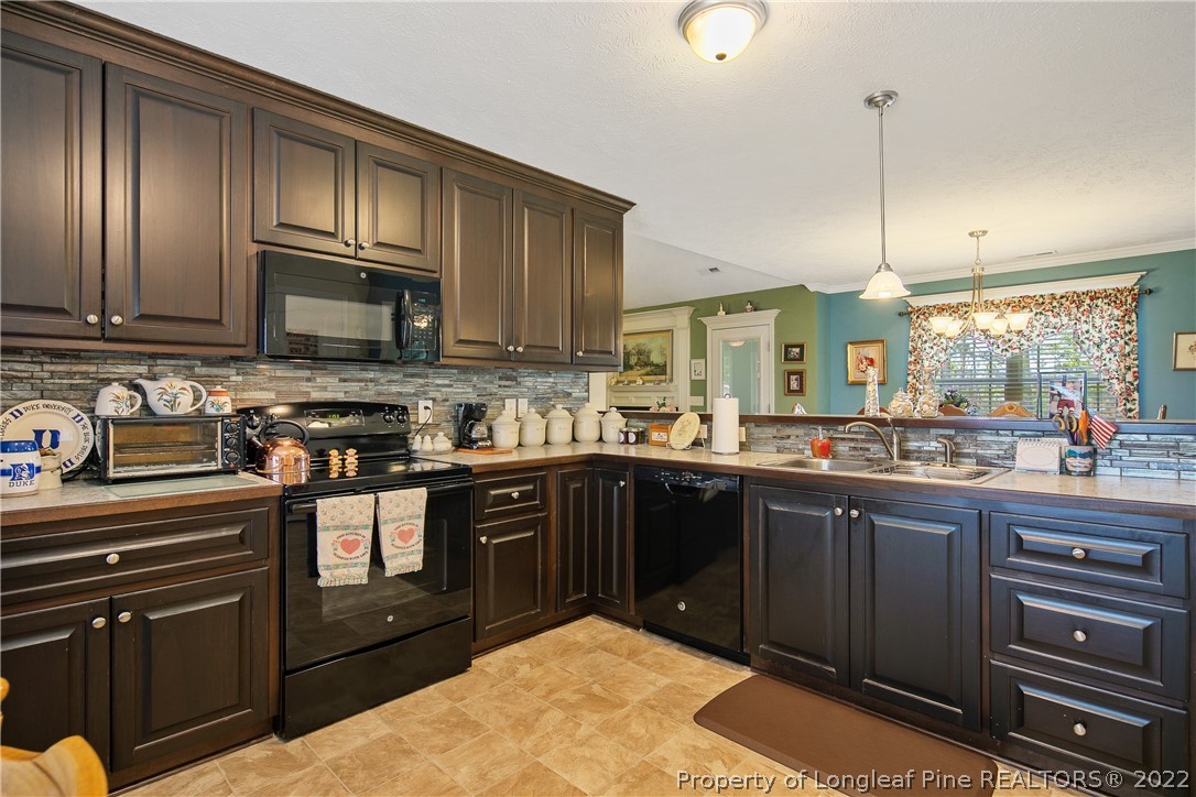 2511 Wade-Stedman Road Stedman, NC 28391 - Photo 14 of 47 a kitchen with stainless steel appliances granite countertop wooden cabinets a stove top oven a granite counter top and a view of living room