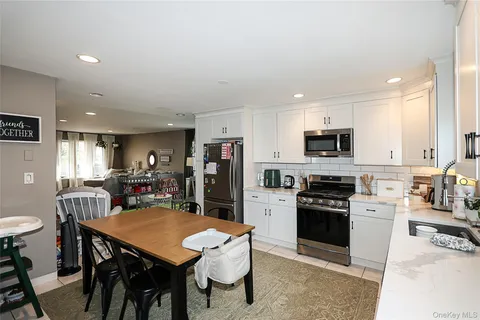 a kitchen with stainless steel appliances a dining table chairs stove refrigerator and cabinets